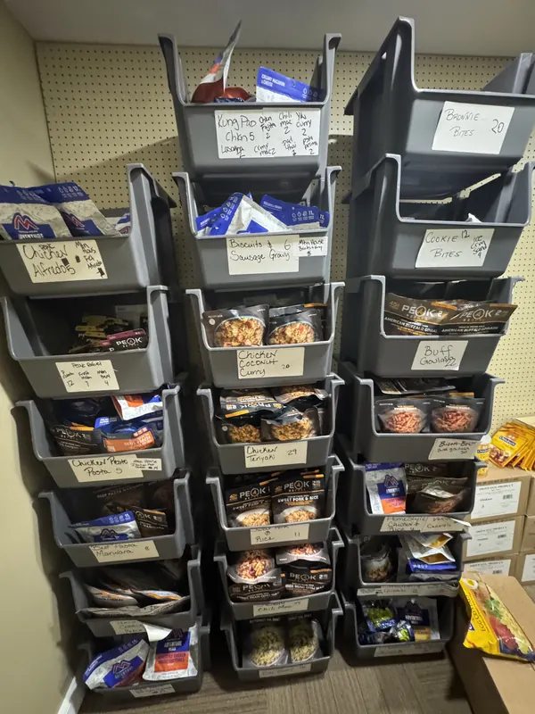 Peak Refuel freeze-dried meal pouches sorted by flavor in labeled stacking bins