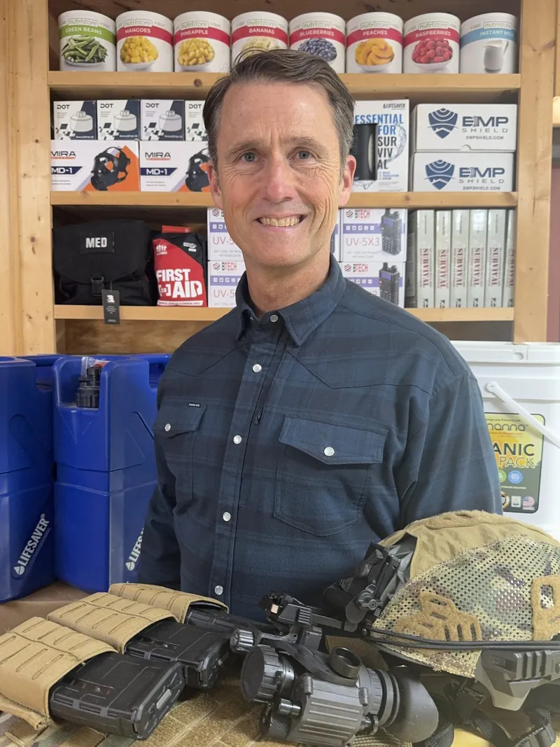 Version 1.1 Chris Koelzer, new owner of Ready Made Resources, in front of shelves of storage food, water containers and preparedness gear